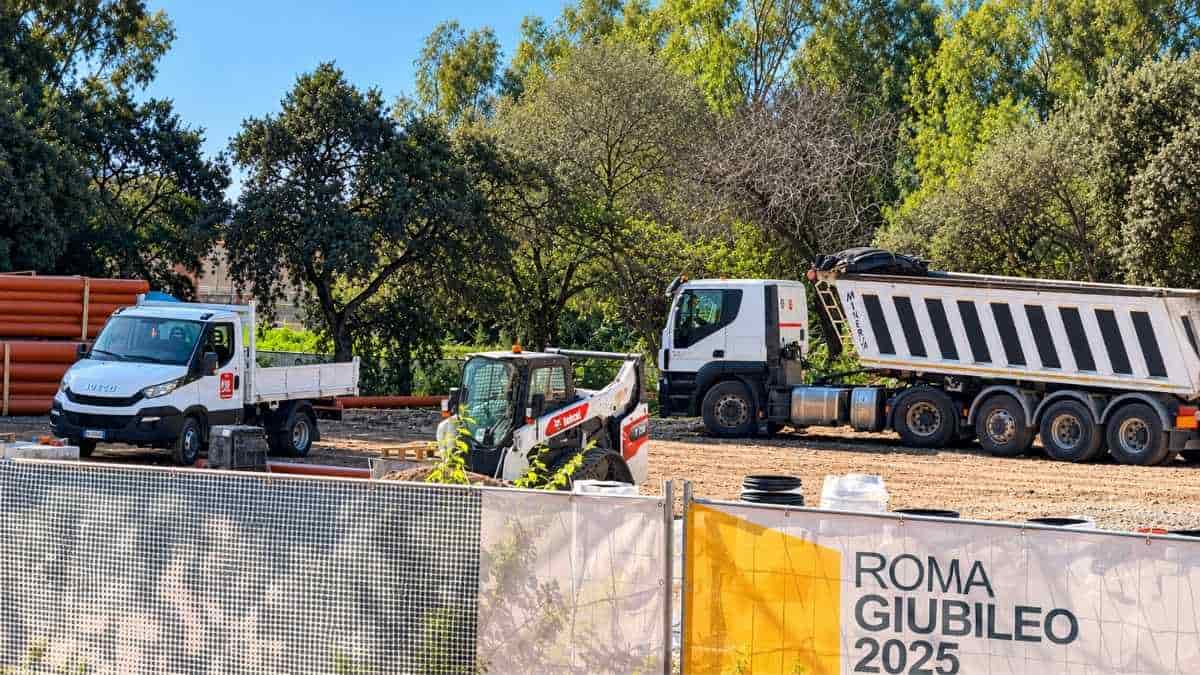 Acilia Sud, cantiere del parcheggio P2 in via Bepi Romagnoni, con recinzioni e cartello del Giubileo 2025.