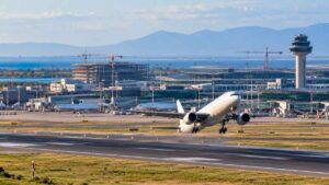 Ricostruzione digitale dell'aeroporto di Fiumicino con un aereo in decollo, piste e infrastrutture aeroportuali sullo sfondo.