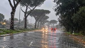 Infernetto, strada allagata dalla pioggia con automobili in transito: immagine illustrativa del maltempo in via Wolf Ferrari.