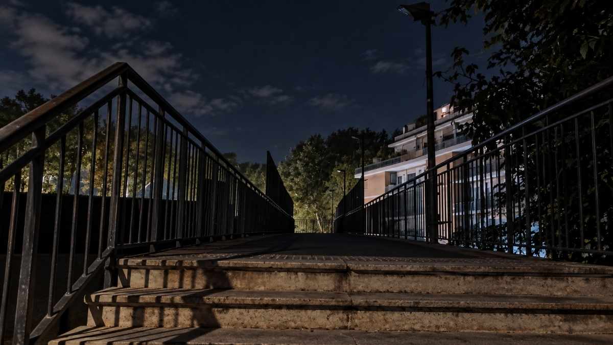Magliana, ponte pedonale al buio tra via Giuseppe Belluzzo e via della Magliana, con scalinata e passerella scarsamente illuminate.