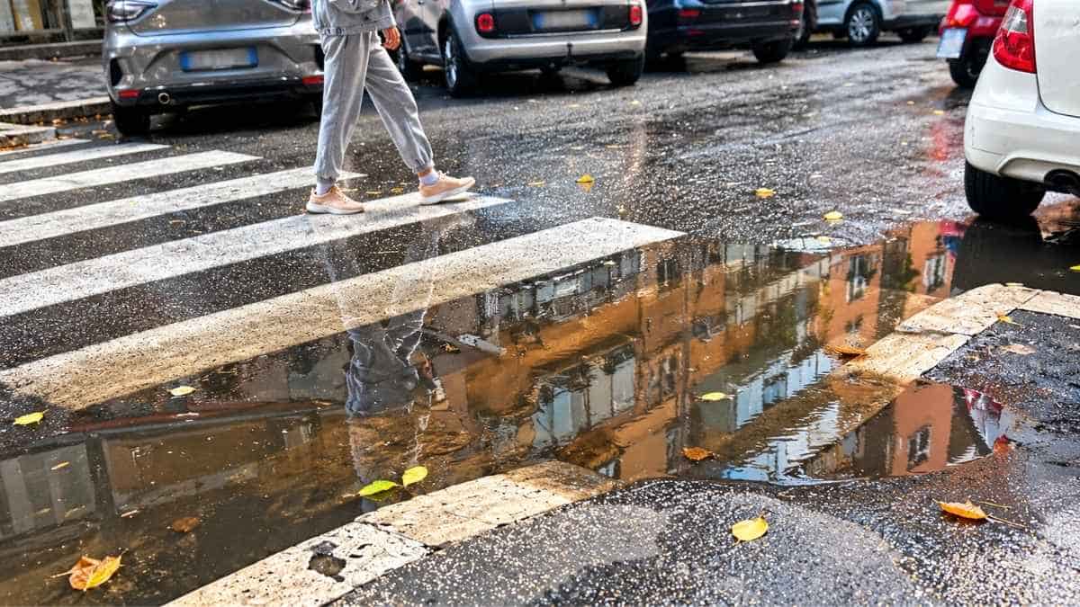 Marconi, attraversamento pedonale allagato tra via Grimaldi e via Aldini a Roma, con acqua davanti allo scivolo del marciapiede.