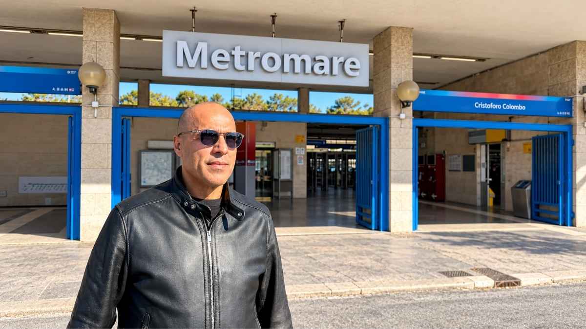 Giuseppe Conforzi davanti alla stazione Cristoforo Colombo della Metromare a Ostia, con l'ingresso ferroviario sullo sfondo.