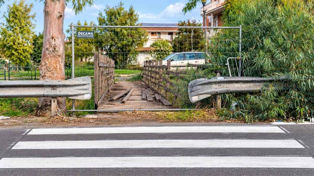 Ostia Antica, strisce pedonali davanti al ponticello in legno chiuso da una recinzione in via del Collettore Primario.