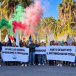 Manifestazione di Giustizia X Ostia contro degrado e insicurezza, con cittadini, striscioni, bandiere e fumogeni tricolori davanti al Municipio X.