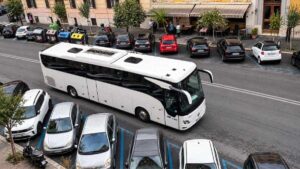 Pullman turistico in via della Giuliana, nel quartiere Prati a Roma, accanto alle automobili parcheggiate lungo la strada.