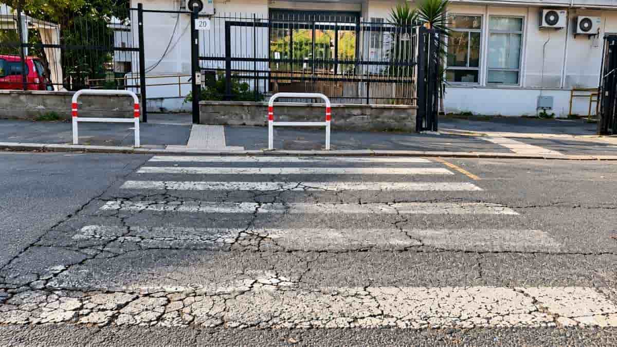 Roma, attraversamento pedonale con strisce sbiadite e asfalto fessurato nell'area di Tor Marancia, nell'VIII Municipio.