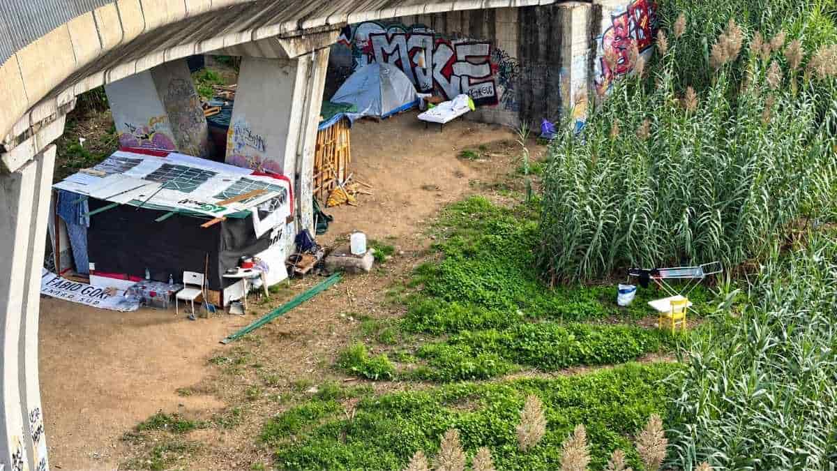 Roma, baracche e tende sotto il cavalcavia di via Portuense, all'altezza di viale Isacco Newton, tra strutture di fortuna e vegetazione.