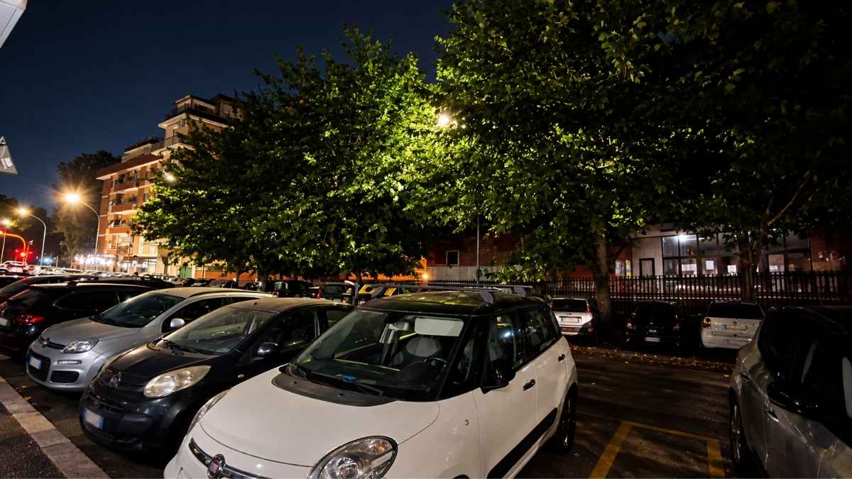 Via Alessandro Cruto a Roma, nel quartiere Marconi, con alberi che coprono i lampioni e la strada poco illuminata