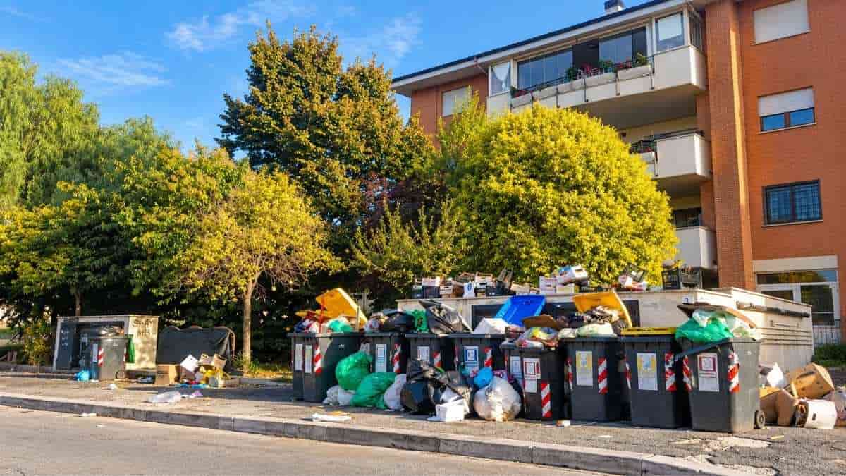 Roma, cassonetti stracolmi di rifiuti con sacchi, cartoni e materiali abbandonati sul marciapiede in via Don Tonino Bello, nel VI Municipio.