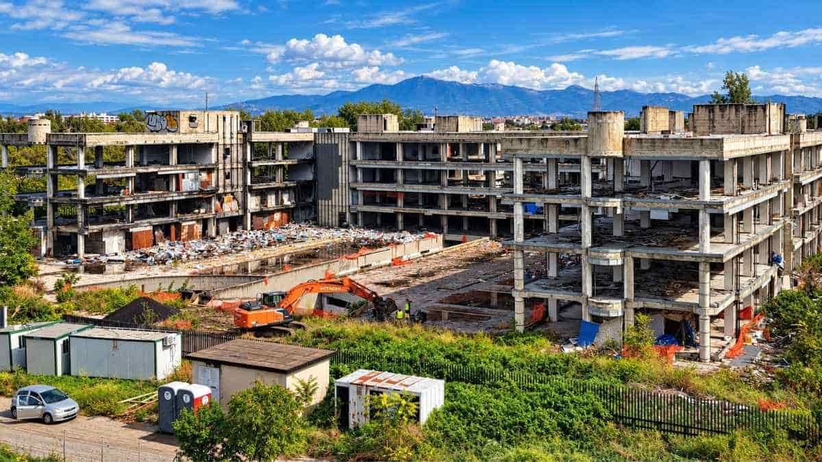 Panoramica degli edifici abbandonati di via Tallone a Tor Sapienza, con un escavatore impegnato nelle operazioni preliminari alla demolizione.